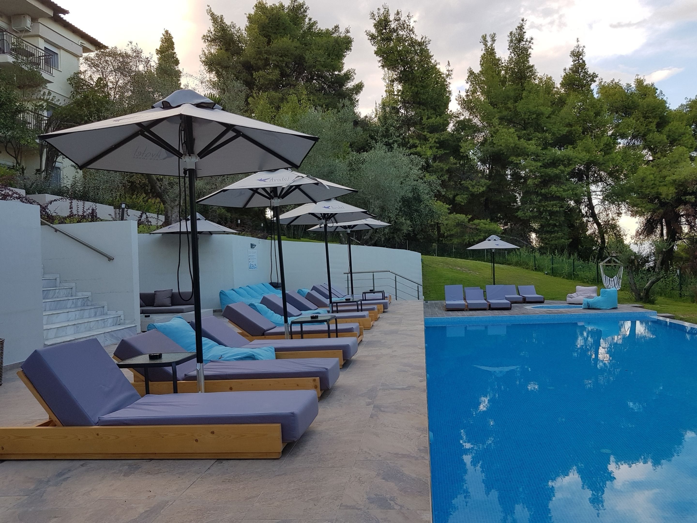 Una piscina al aire libre, sombrillas, sillones reclinables de piscina
