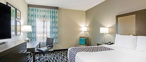 Een hotelkamer met een bed, bureau, stoel en twee bedlampjes.