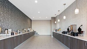 Eine moderne Küche mit grauen Schränken, einer gefliesten Spritzschutzleiste und einer langen Arbeitsfläche mit verschiedenen Geräten und Utensilien.