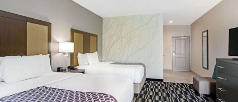 Une chambre d’hôtel avec deux lits, un téléviseur à écran plat, une commode et une moquette à motifs.