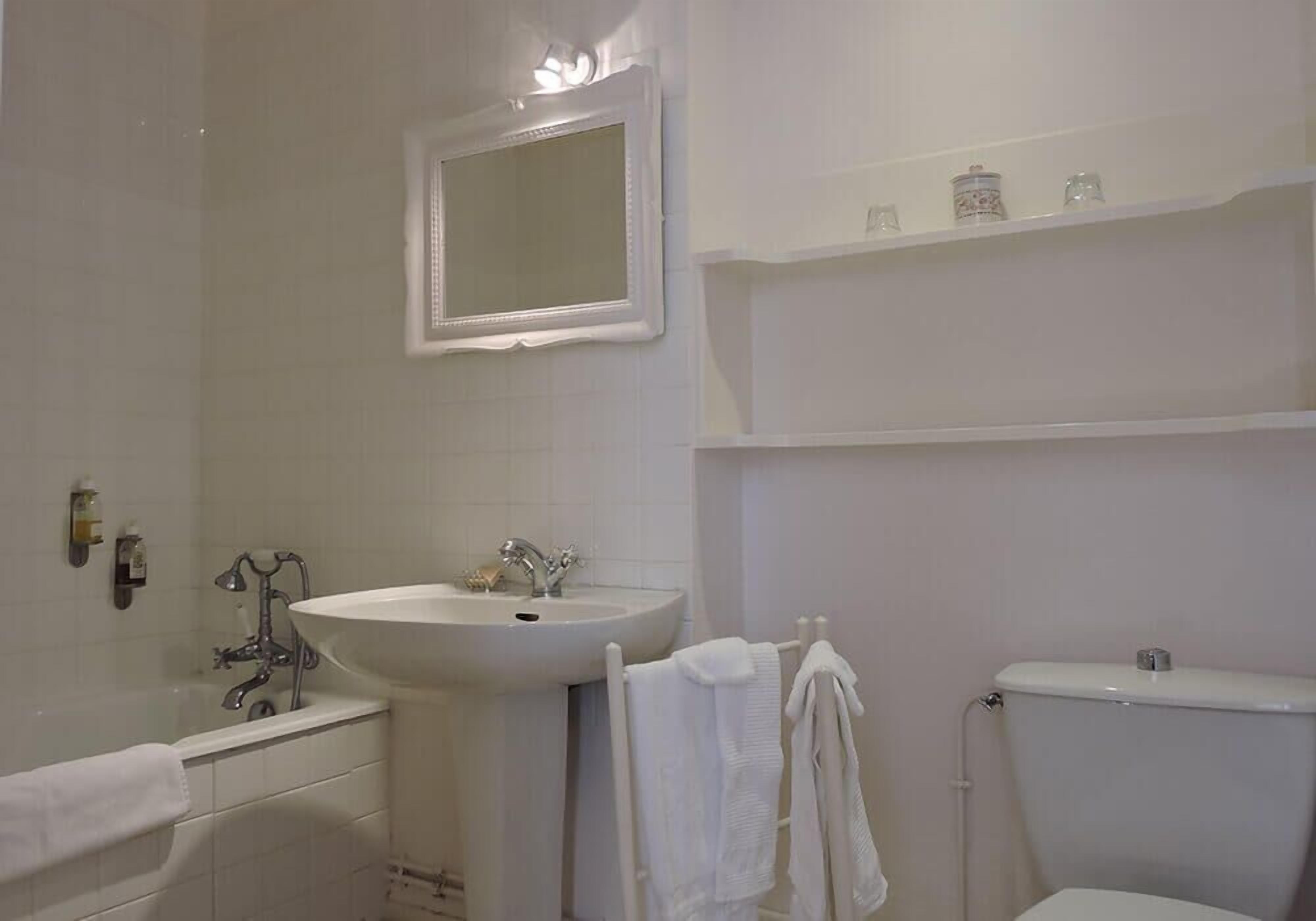 A bathroom with a white sink, a mirror, a toilet, and a bathtub.