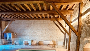 An indoor swimming pool with a stone wall and wooden beams. - Le Domaine de Mestré, The Originals Relais  (Fontevraud-l'Abbaye)