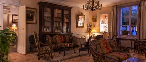 Un salon traditionnel avec une cheminée, un lustre et une grande bibliothèque.