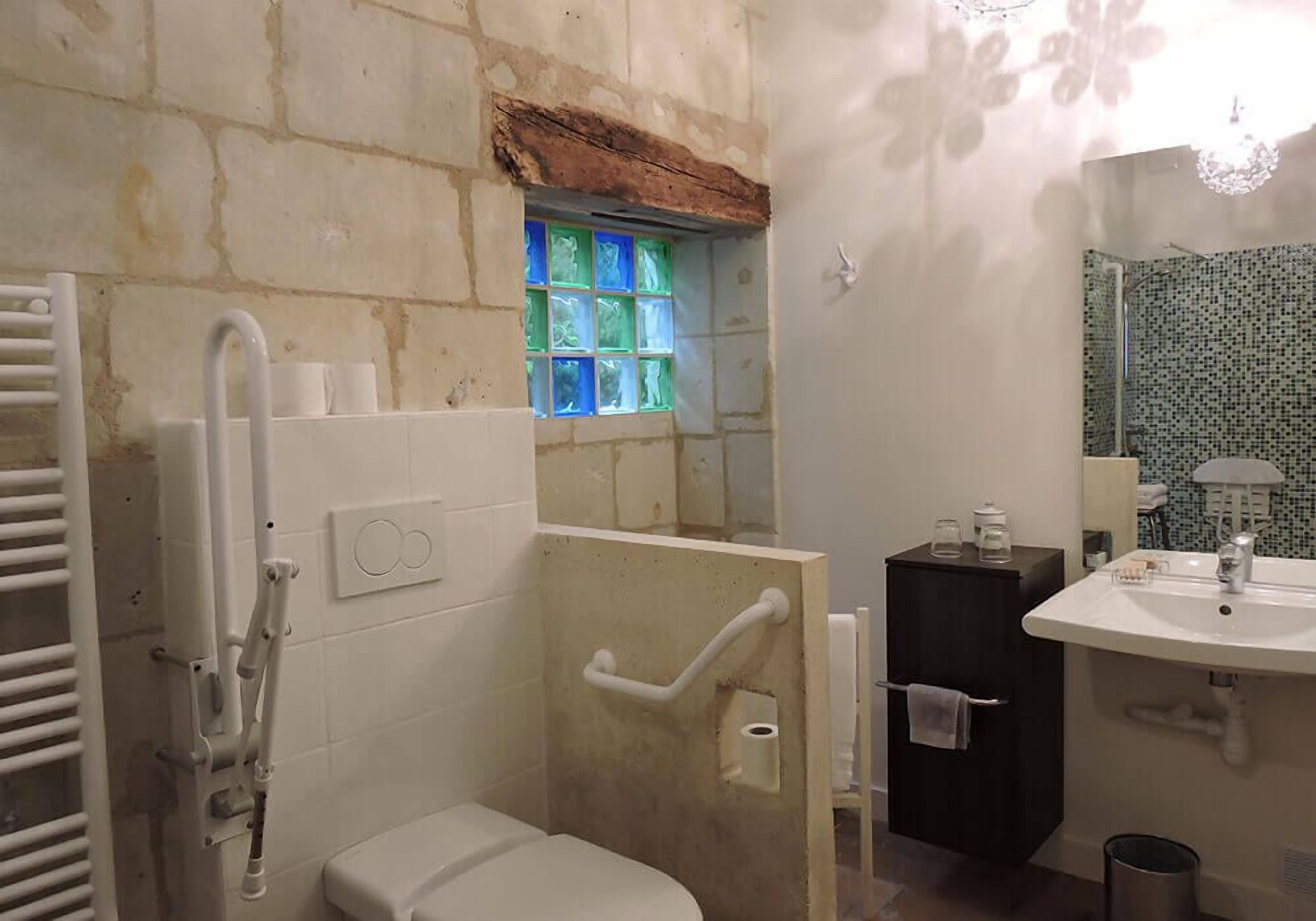 Un baño con inodoro, zona de ducha con ventanal de vidrio, lavabo y espejo.