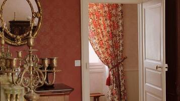 Una habitación con espejo, cómoda y puerta con cortinas florales.
