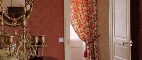 Una habitación con espejo, cómoda y puerta con cortinas florales.