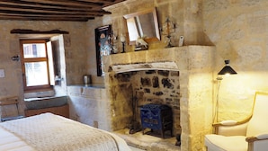 A cozy room with a stone fireplace, a bed, a chair, and a wooden ceiling. - Le Domaine de Mestré, The Originals Relais  (Fontevraud-l'Abbaye)