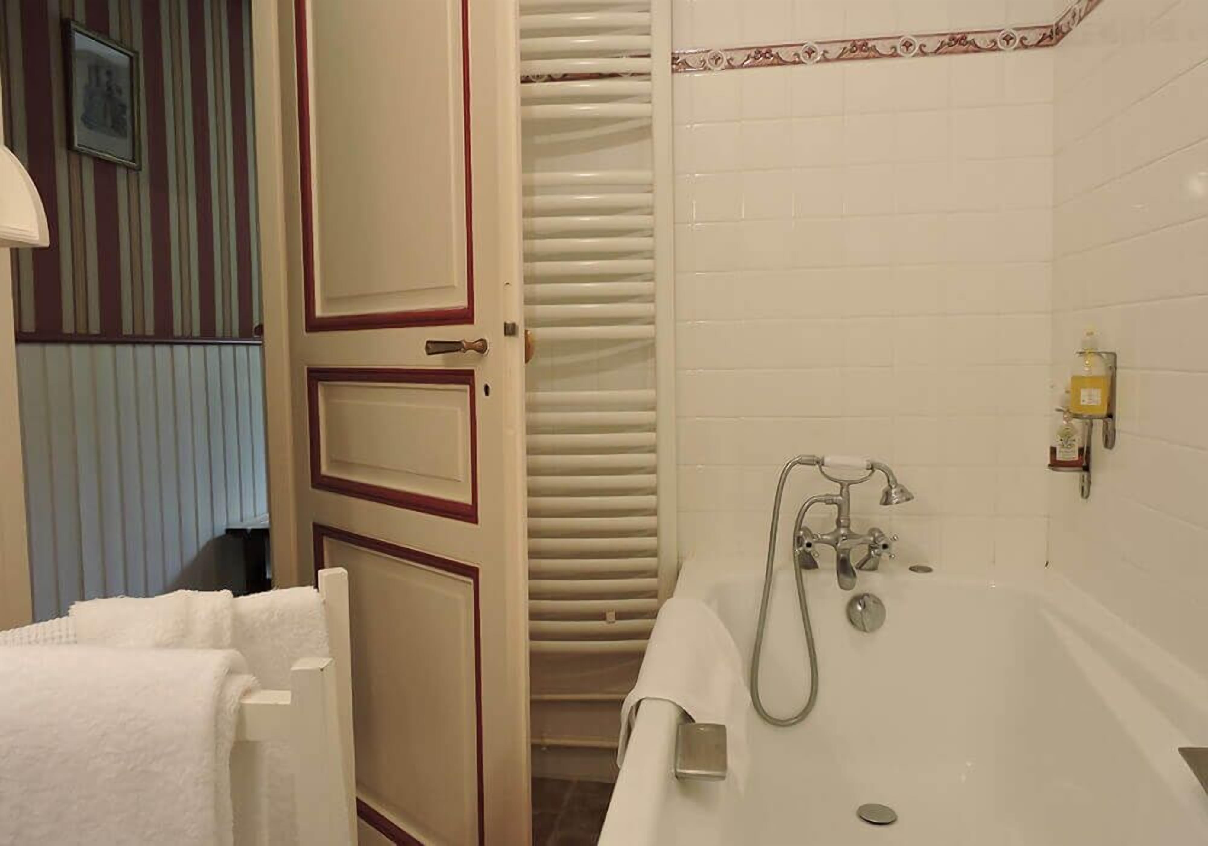 Un baño con bañera, toallero y un inodoro.