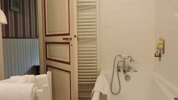 Un baño con bañera, toallero y un inodoro.