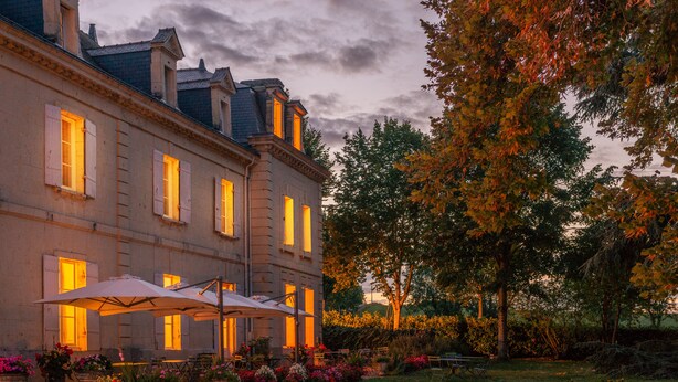 A large building with multiple windows and a well-maintained garden with outdoor seating. - Le Domaine de Mestré, The Originals Relais  (Fontevraud-l'Abbaye)
