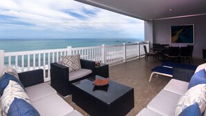 Un balcon avec vue sur l’océan, aménagé avec un canapé, une table et des chaises.