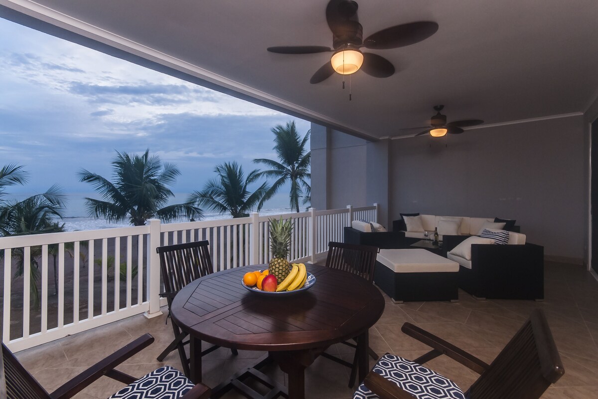 A balcony with a table set with fruit, a sofa, and a ceiling fan.