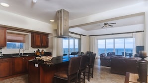 A spacious kitchen with a large island, dark wooden cabinets, and a view of the ocean. - Vistas Las Palmas by Dream Makers (Jacó)