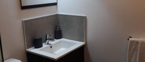 Un baño pequeño con un lavamanos blanco, un espejo y una toalla colgada en la pared.