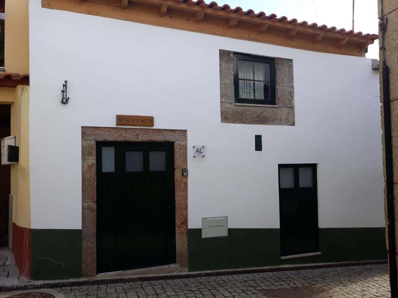 A building with a large black door, a smaller door, and a window. There is a sign above the large door that reads "Refugio D'Anita."