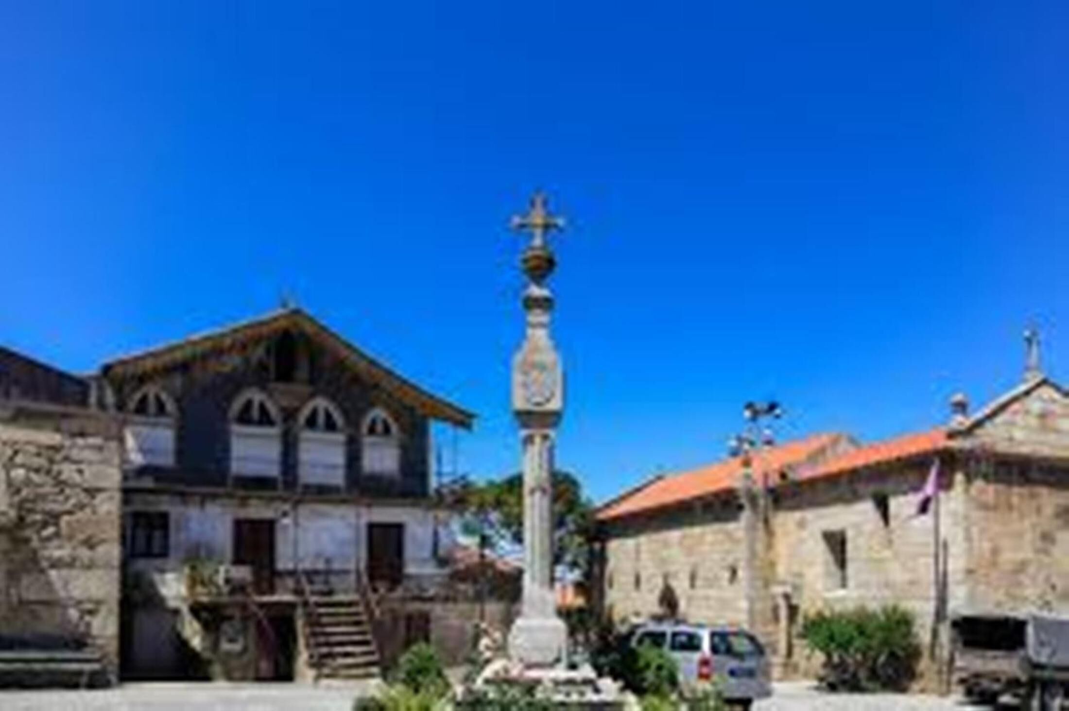 A historic building with a stone facade, a central monument, and a red-tiled roof.