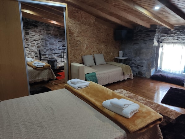 A cozy room with a bed, a massage table, and a stone wall. - Refúgio D'Anita Douro valley house (Tabuaço)