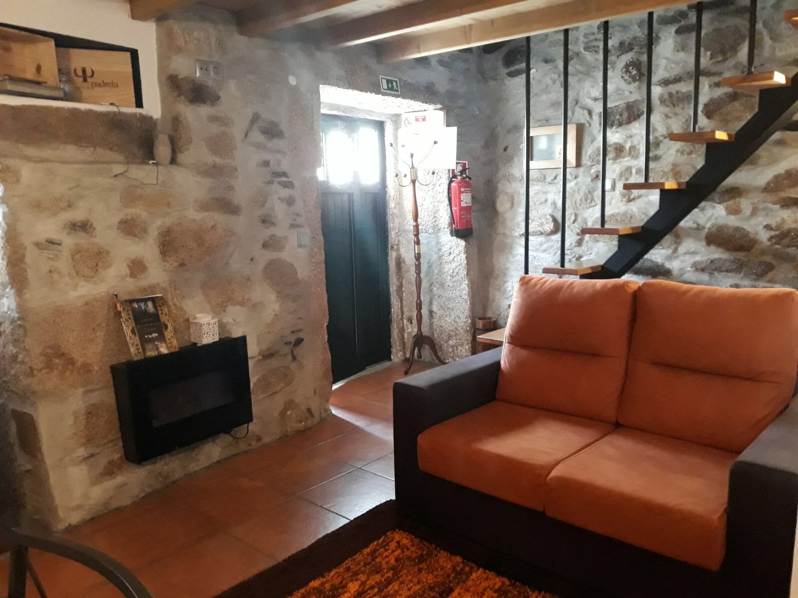 Una sala de estar acogedora con una pared de piedra, una chimenea, un sofá y una escalera.