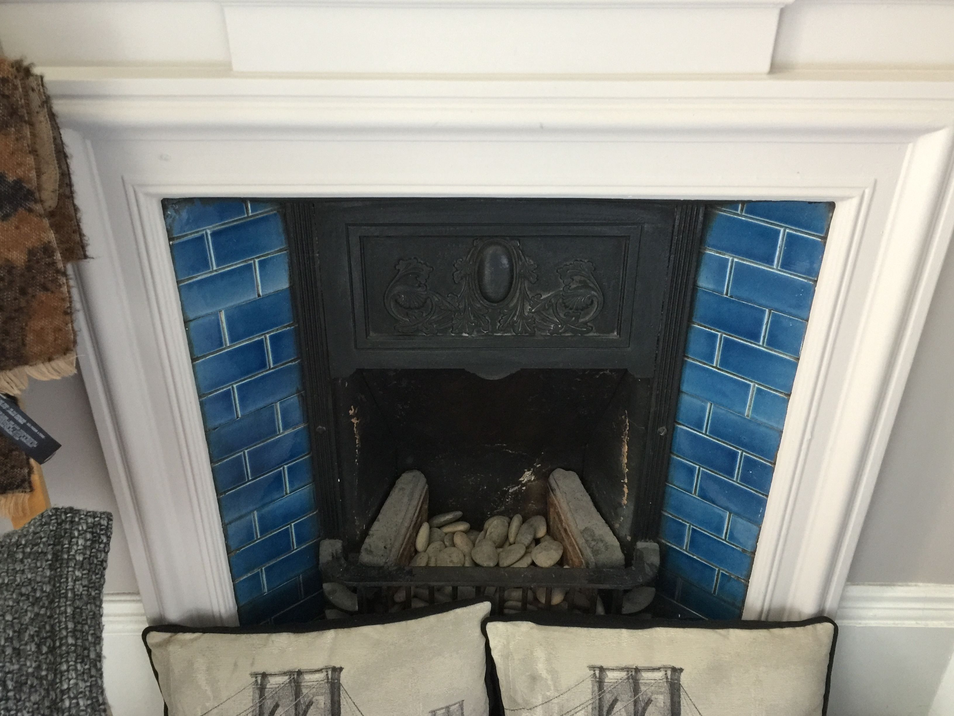 A fireplace with blue tiles, a decorative mantel, and a log fire.