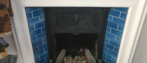 A fireplace with blue tiles, a decorative mantel, and a log fire.