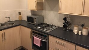 Une cuisine moderne équipée d’une cuisinière à gaz, d’un four à micro-ondes, d’un four traditionnel et d’une hotte en acier inoxydable.