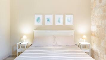 Um quarto com uma cama, duas mesas de cabeceira e uma parede de pedra.