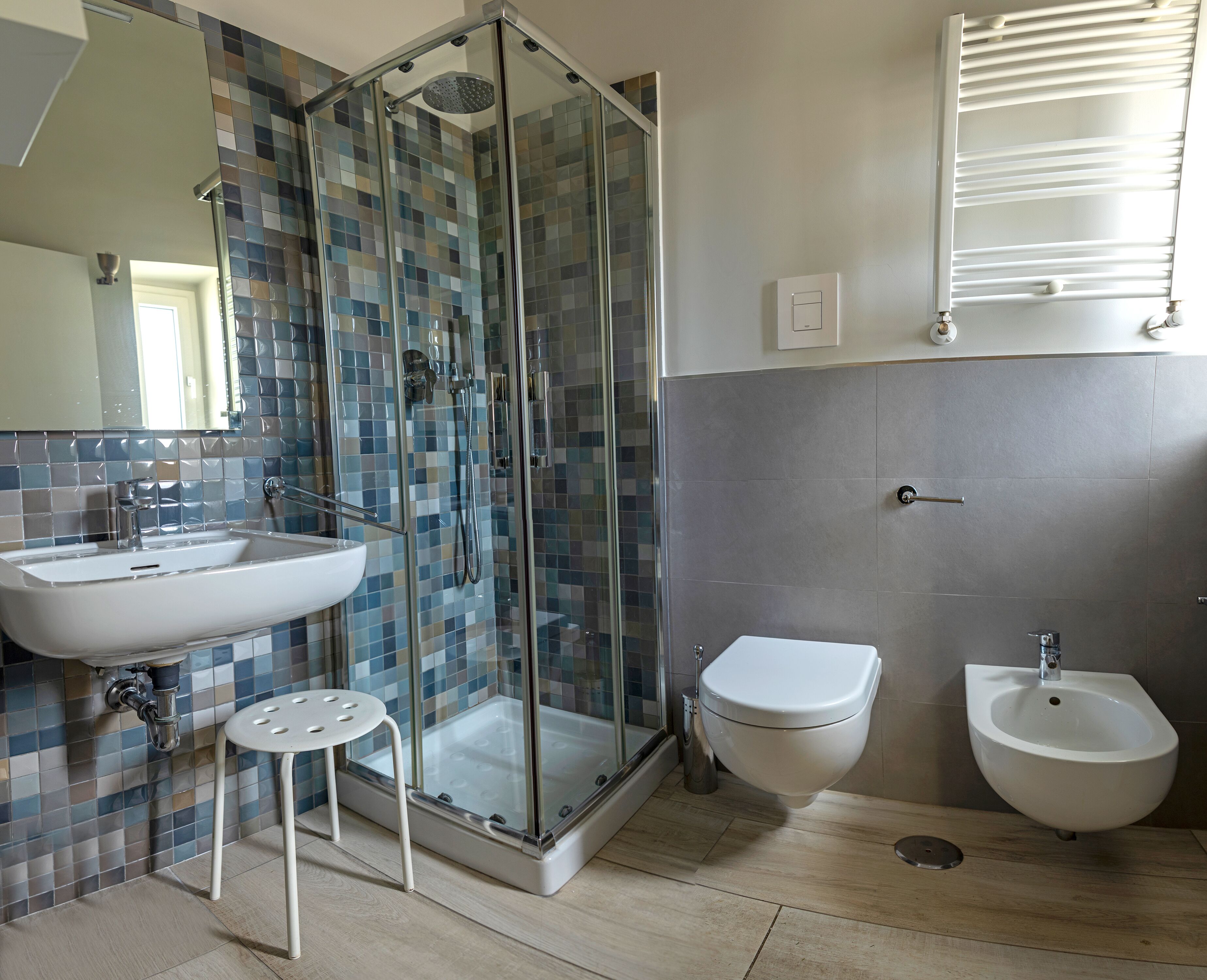 A modern bathroom with a glass-enclosed shower, a sink, a toilet, and a bidet.