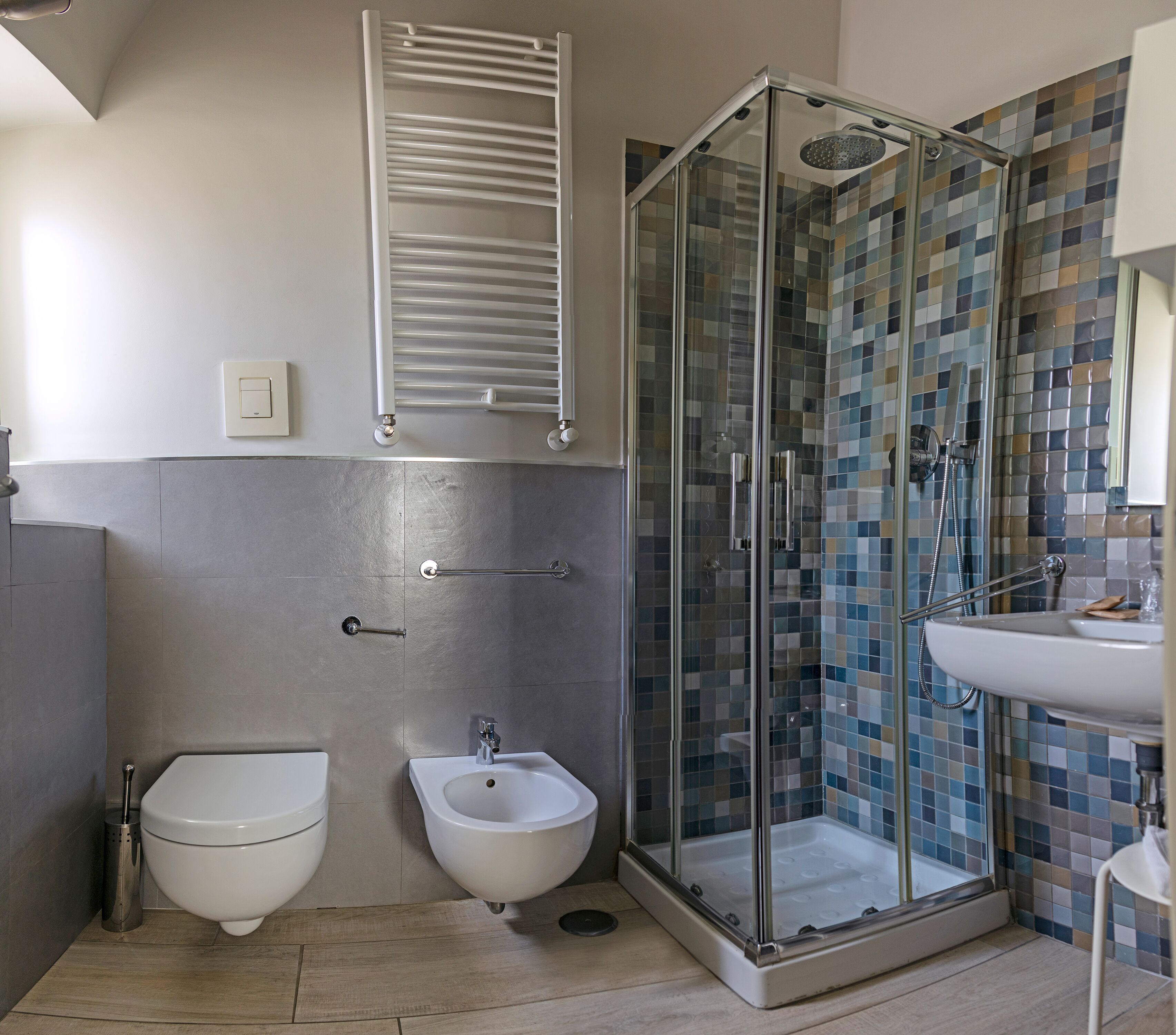 Un baño moderno con ducha acristalada, un bidé y un lavamanos.