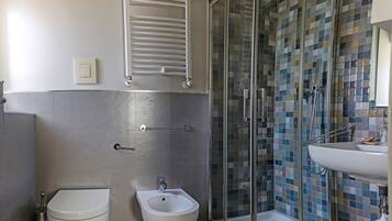 Un baño moderno con ducha acristalada, un bidé y un lavamanos.
