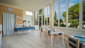 Cocina luminosa con armarios de madera, un reloj y una ventana con vistas a la vegetación.