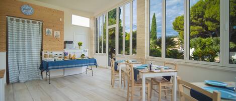 A bright kitchen with wooden cabinets, a clock, and a window overlooking greenery.