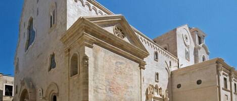 A historic building with a central courtyard, featuring a grand staircase leading to an entrance with a wooden door.