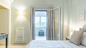 Habitación de hotel con cama, escritorio, silla y vista a un balcón.