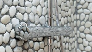 A shower with a pebbled wall and a metal shower head. - Rome Services Borgo Suites (Rome)