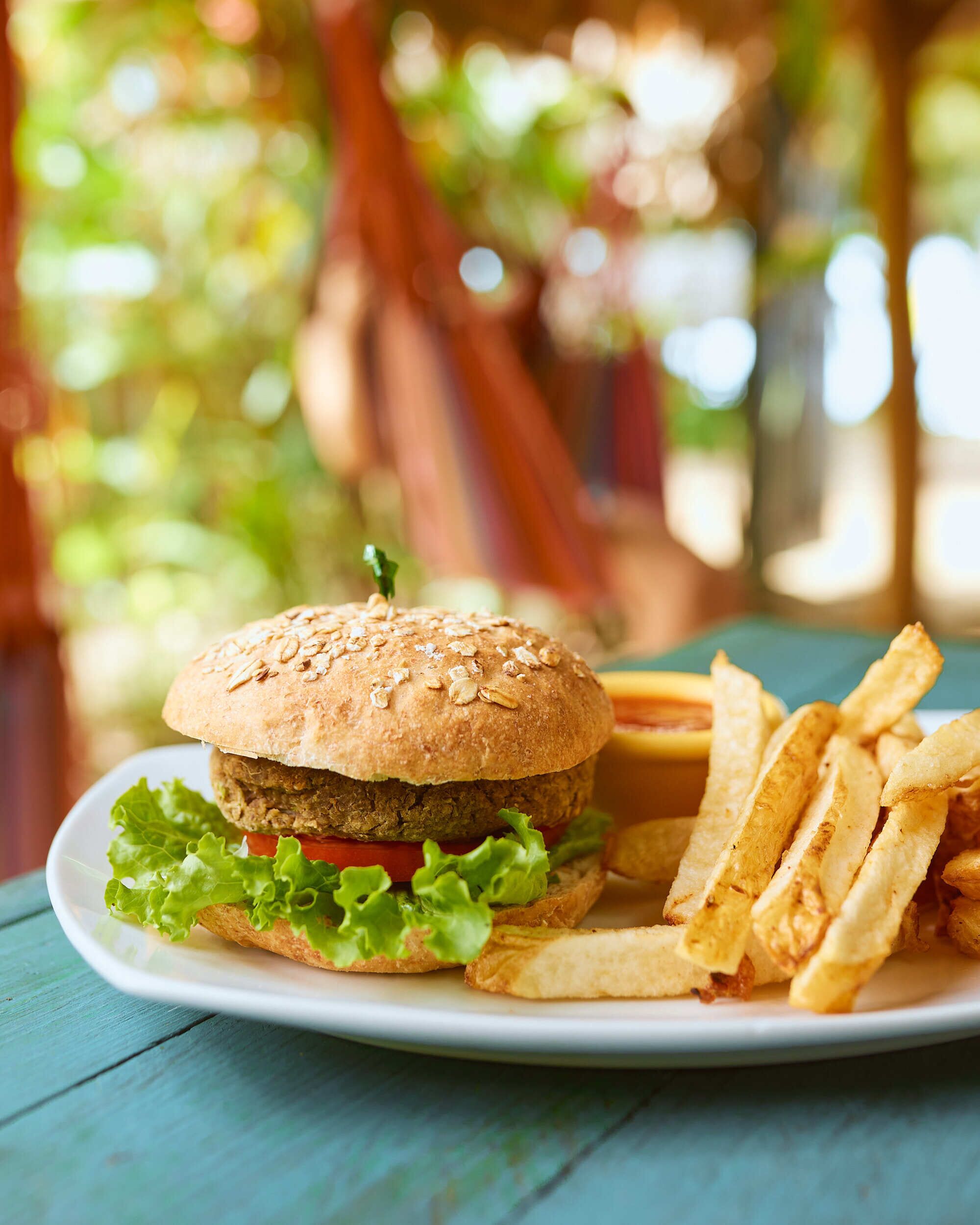 A burger with lettuce and a bun on a plate, accompanied by French fries.