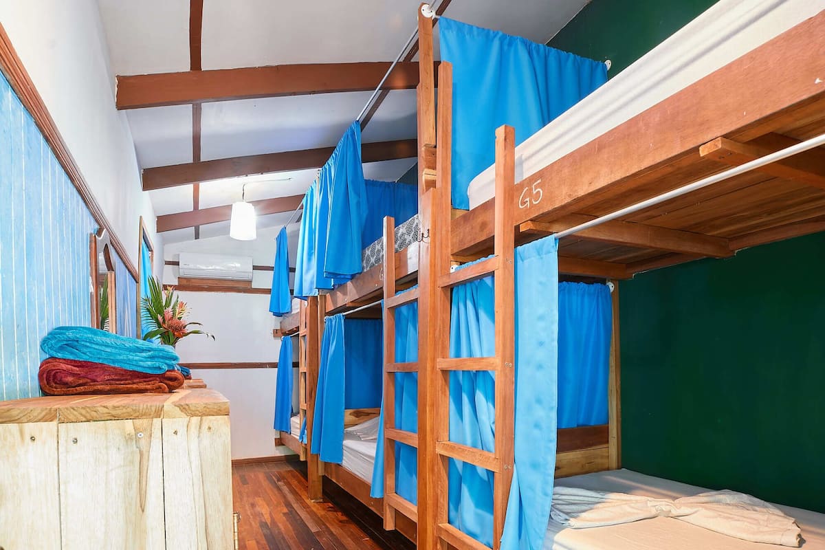 Une chambre de dortoir avec des lits superposés, un plancher en bois et des rideaux bleus.
