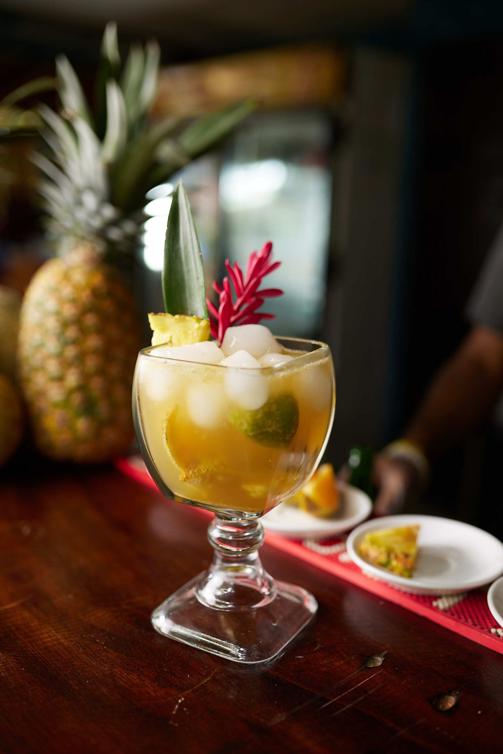 A cocktail with a pineapple garnish on a wooden bar counter.