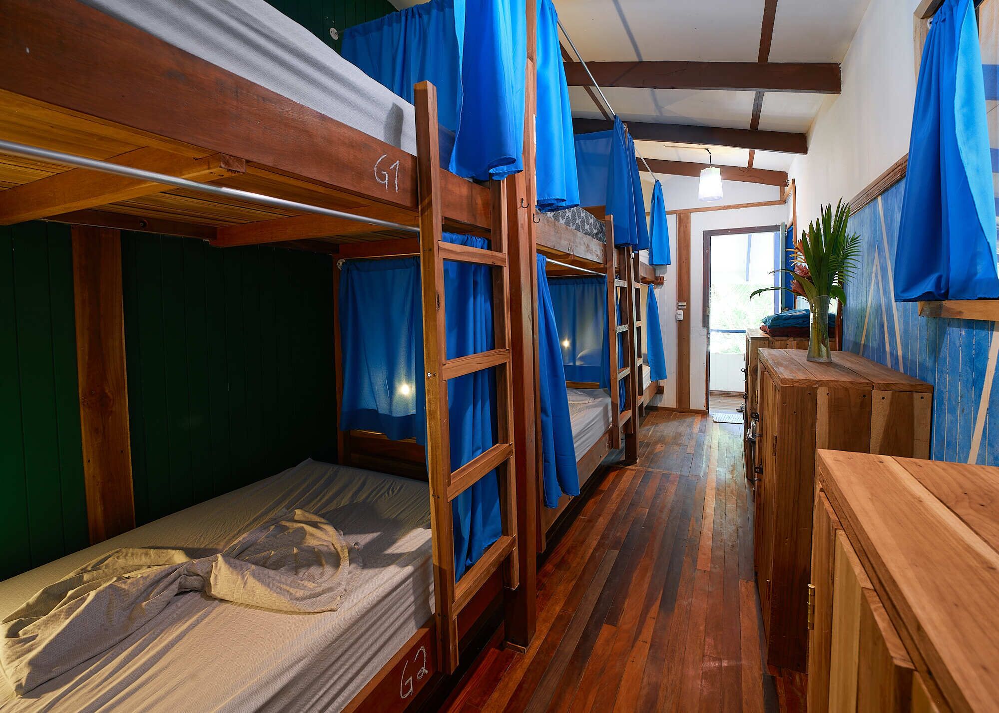 Habitación con literas, pisos de madera y cortinas azules.