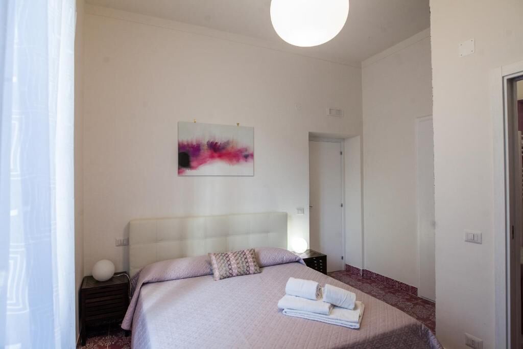 A bedroom with a bed, a bedside table, a wall-mounted artwork, and a door.