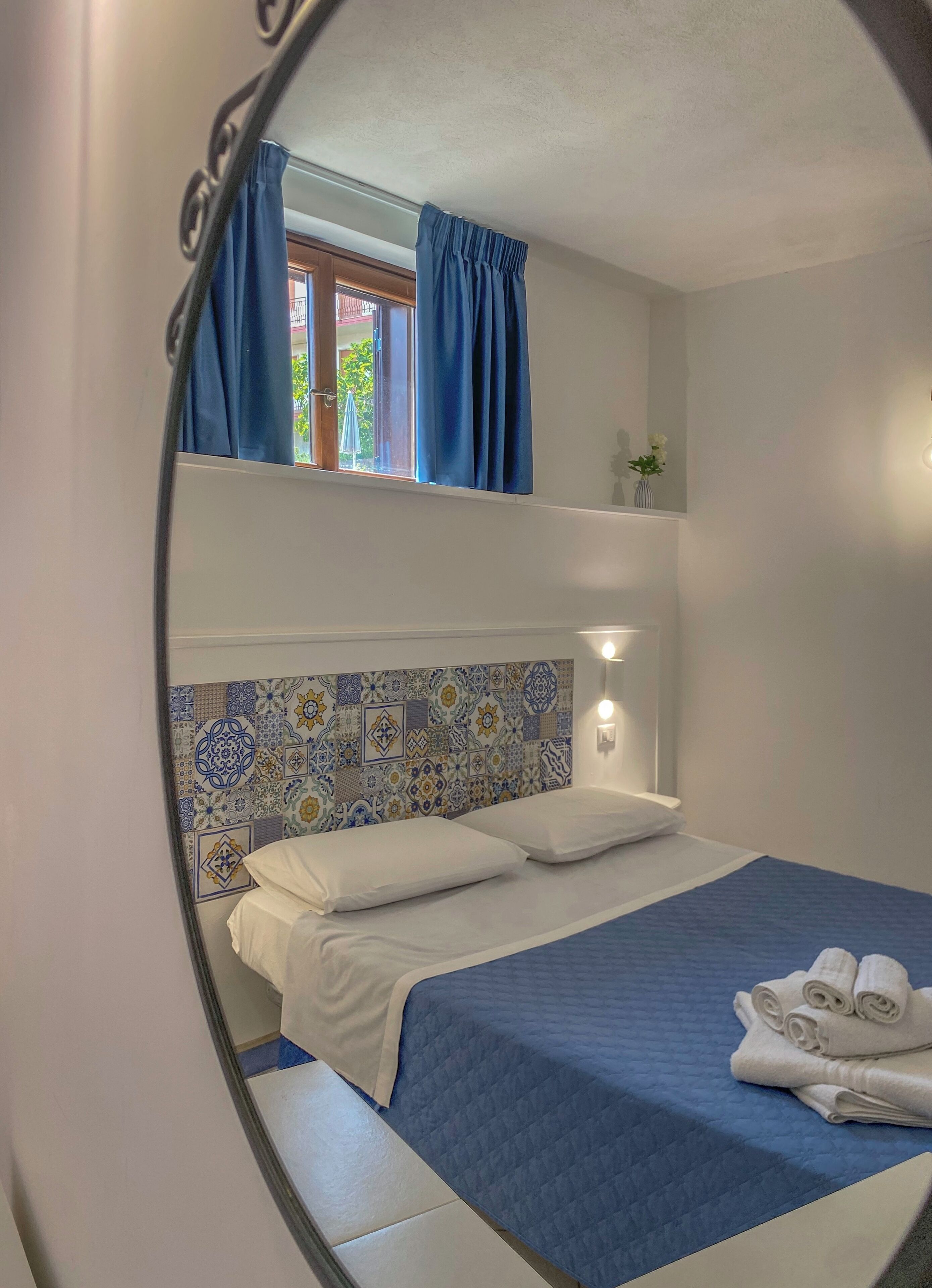 Ein Einzelbett mit einer blauen Bettdecke, weißen Kissen und einem blauen Vorhang.