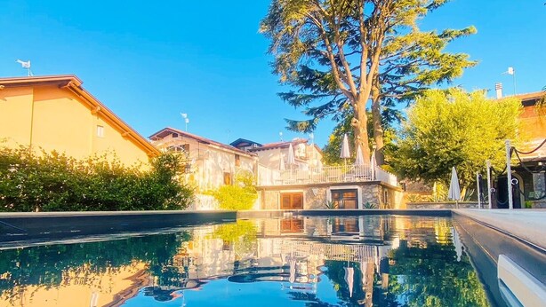 Una piscina con riflessi chiari, circondata da edifici e alberi.