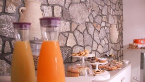 Un ricco buffet della colazione con dolci assortiti e uno sfondo a parete in pietra.