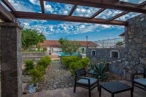 A covered patio with stone walls, a pool, and outdoor seating.