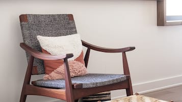 A wooden chair with a woven seat and backrest, a small stool, and a framed artwork on the wall.
