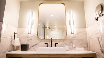 A bathroom with a large mirror, a sink, and a towel rack.