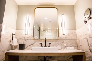 A bathroom with a large mirror, a sink, and a towel rack.