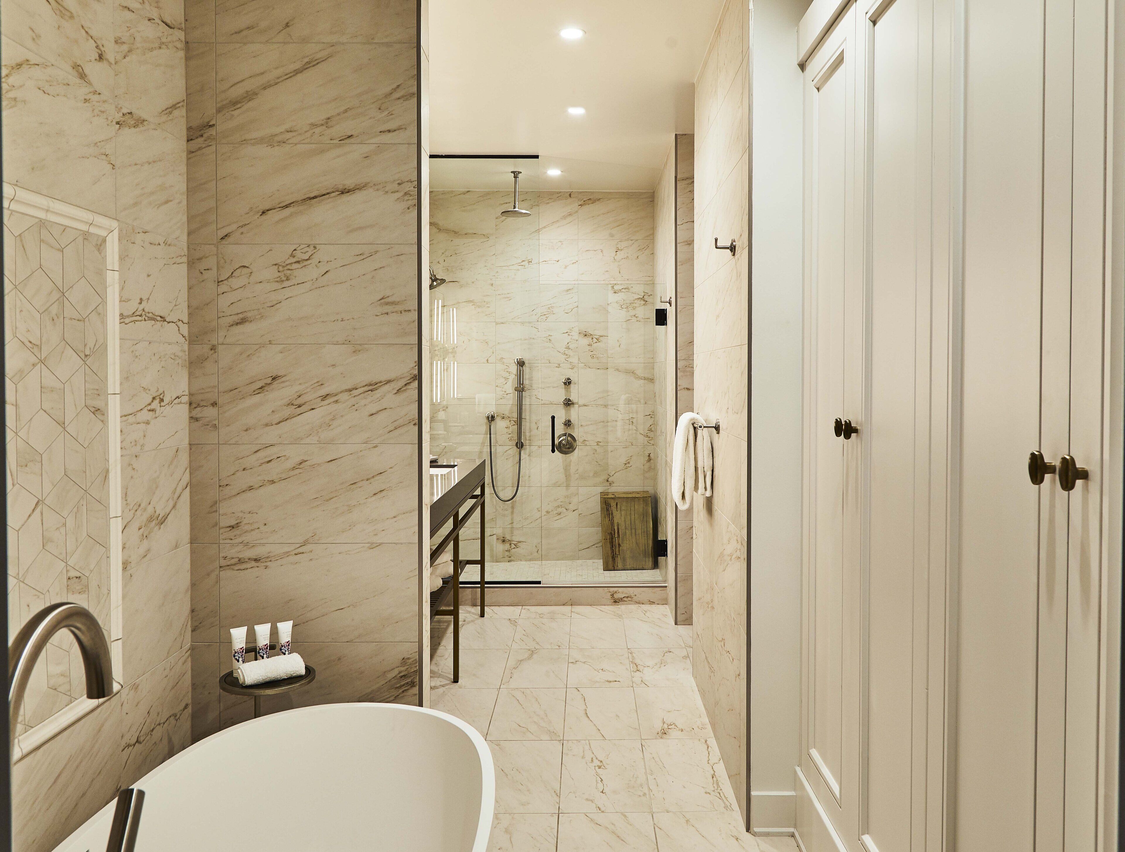 Une salle de bain moderne avec une baignoire sur pieds, une douche à l’italienne et un meuble-lavabo avec un miroir.