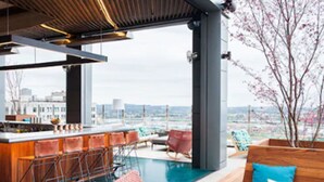 Un bar moderno en la azotea con piscina, taburetes y zonas de estar.