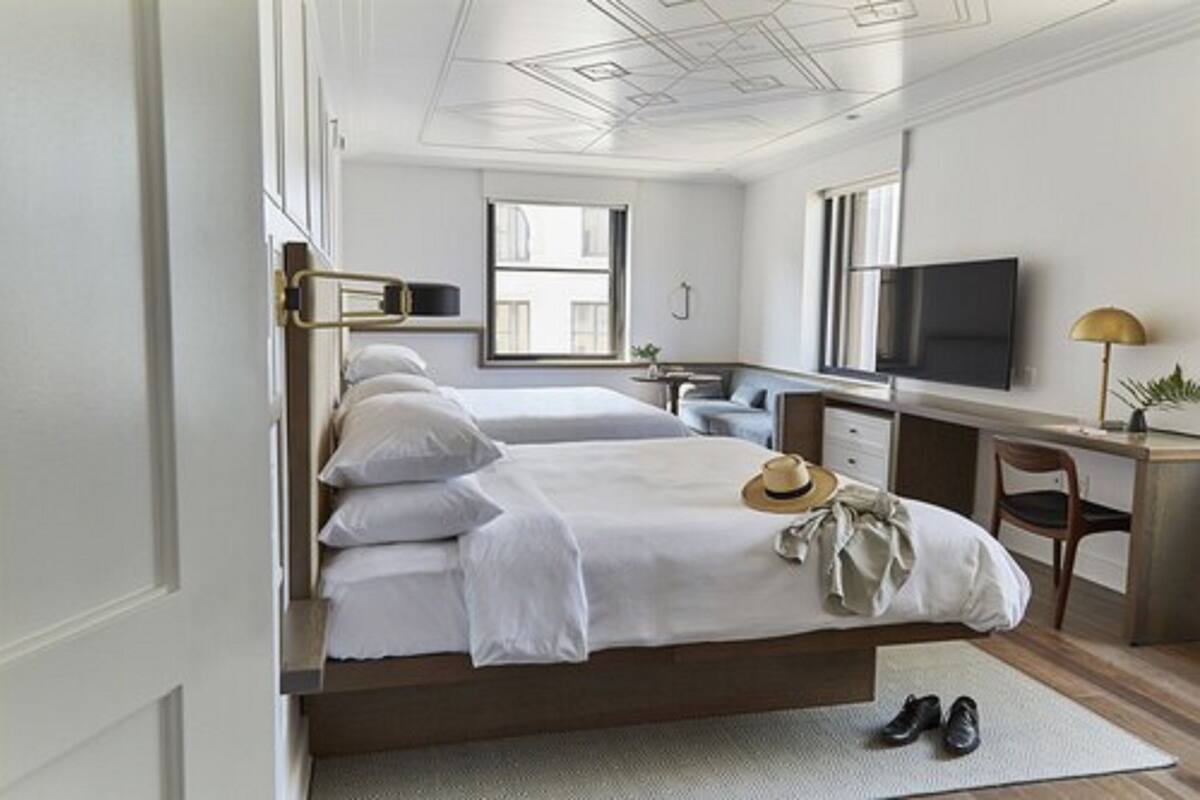 A hotel room with a bed, a desk, a television, and a window.