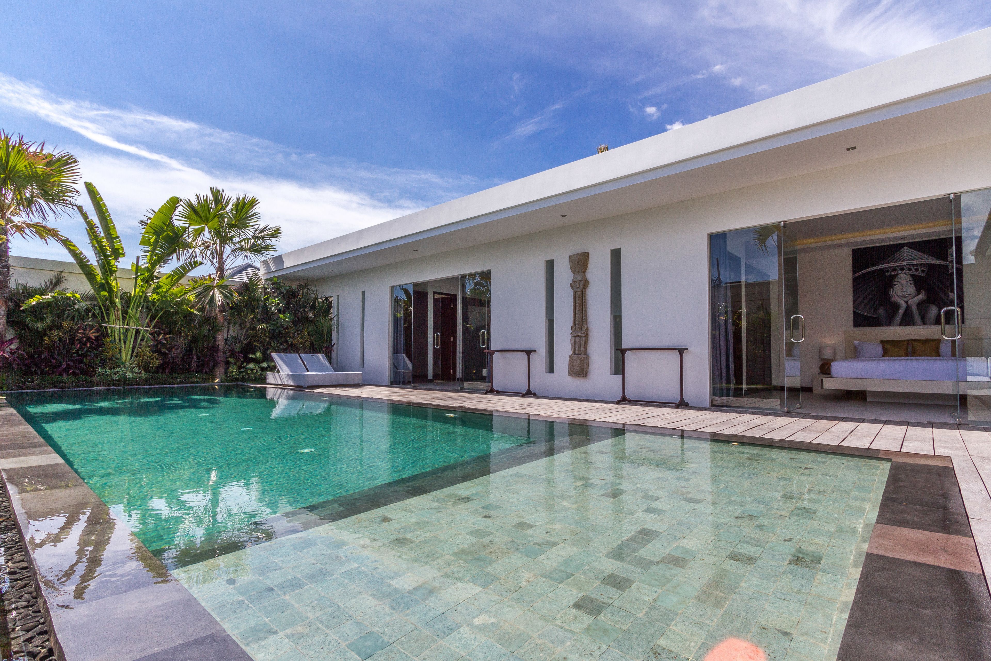 Una casa moderna con piscina, puerta de entrada de vidrio y una cama visible a través del cristal.
